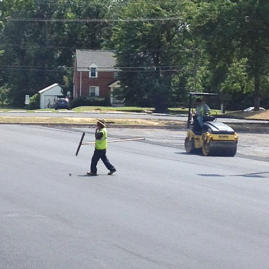 A man in yellow vest walking across street.