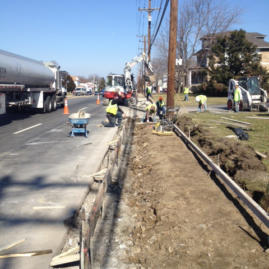 A road with construction workers and utility poles.